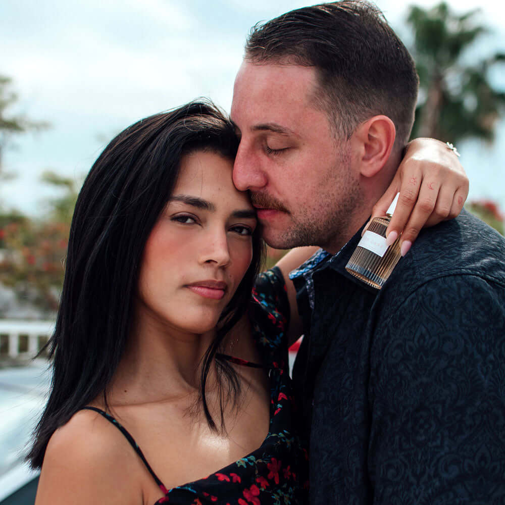 Couple embracing with EOL-P-05DX_6 perfume bottle.